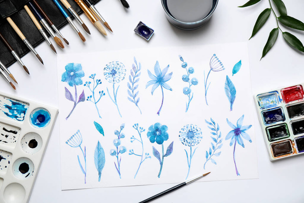 Flat lay composition with floral picture and watercolor paints on white background - 写真・画像