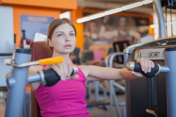 Mujer haciendo entrenamiento de fitness en la máquina de empuje de extensión de mano con pesas
 - Foto, imagen