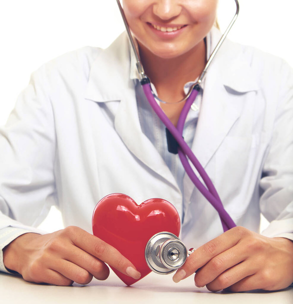Female doctor with stethoscope holding heart, on light background - Φωτογραφία, εικόνα