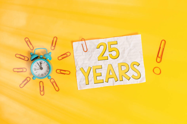 Wortschreibtext 25 Jahre. Business-Konzept für die Erinnerung oder Ehrung besonderer Tag für sein 25-jähriges Bestehen Metall Vintage-Alarmclips zerkleinert Blatt Gummiband farbigen Hintergrund. - Foto, Bild