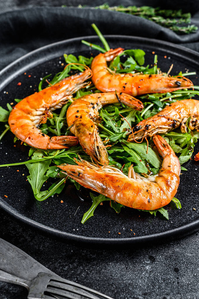 Salad with grilled giant tiger shrimps, prawns and arugula. Black background. Top view. - Photo, Image