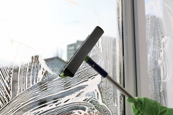 Femme nettoyage fenêtre avec raclette à l'intérieur, gros plan
 - Photo, image