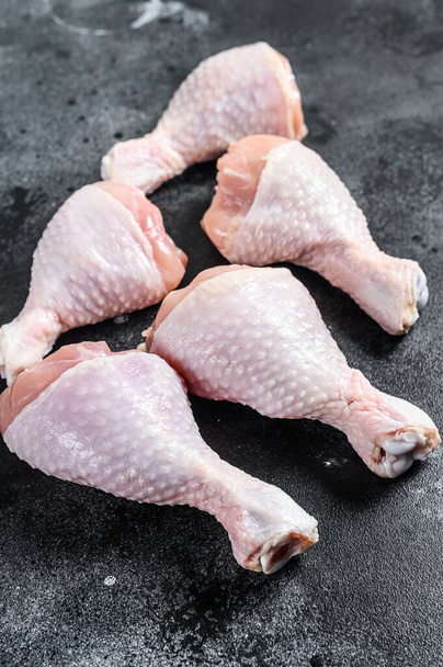 Palitos de pollo frescos, patas en la mesa de la cocina. Carne ecológica de aves. Fondo negro. Vista superior
. - Foto, Imagen