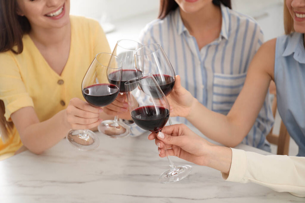 Beautiful young ladies clinking glasses of wine in kitchen, closeup. Women's Day - Foto, imagen