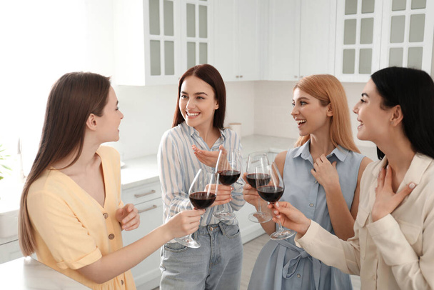 Beautiful young ladies with wine in kitchen. Women's Day - Foto, Imagen