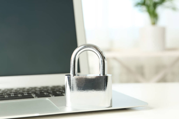 Metal lock and laptop on table, closeup. Protection from cyber attack - Foto, imagen