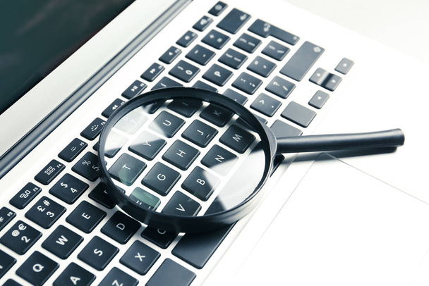 Magnifying glass and modern laptop on table, closeup. Search concept - Фото, зображення