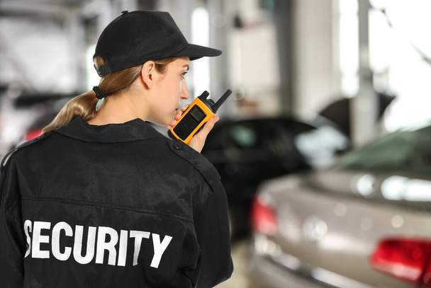 Security guard using portable radio transmitter in automobile repair shop, space for text - Photo, image