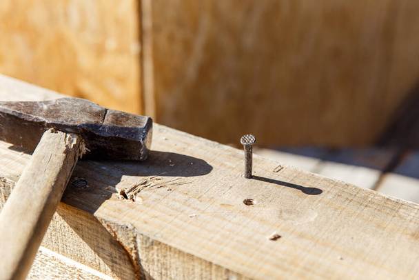 Carpenters uses a hammer to driving nail, Craftsmen and builder equipment. A man hammers an iron nail into a wooden beam - Valokuva, kuva