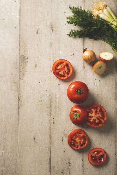 Açık renkli ahşap yüzeyde taze domates, dereotu ve soğan. - Fotoğraf, Görsel