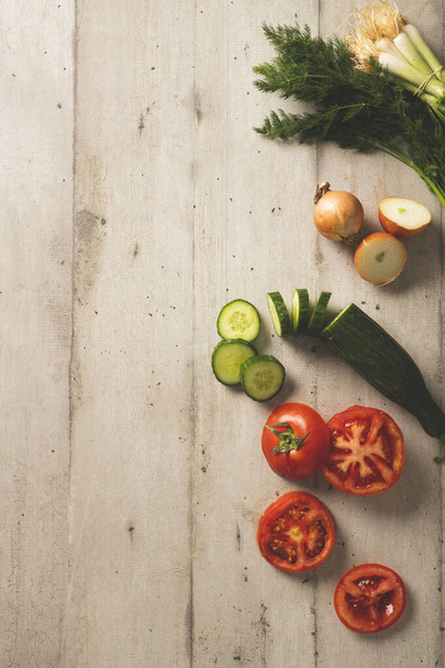 Tomaten- und Gurkenscheiben mit frischen Zwiebeln und Dill auf einem hölzernen Hintergrund - Foto, Bild