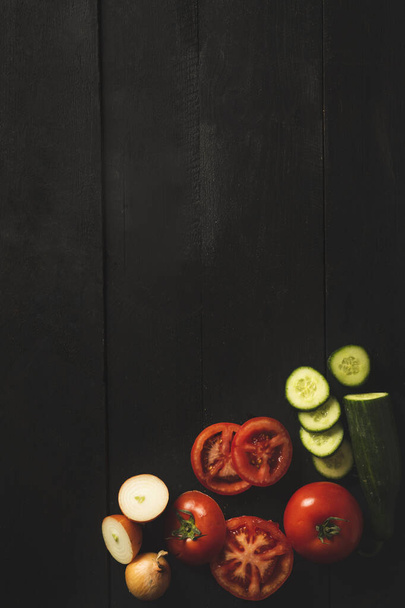 Tomates, pepinos y cebollas sobre un fondo de madera negro
 - Foto, Imagen
