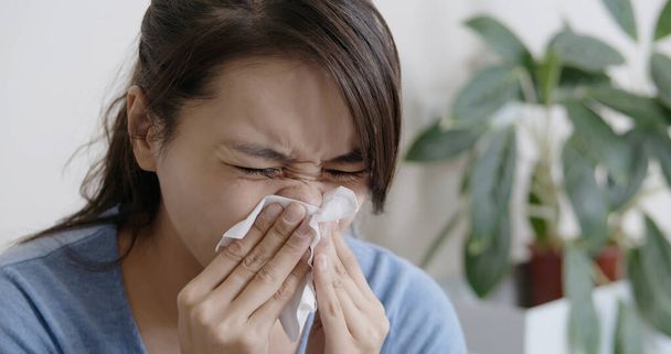 Κοντινό πλάνο της Ασιάτισσας άρρωστης και φτέρνισμα με χαρτί υγείας στο σαλόνι - Φωτογραφία, εικόνα
