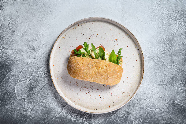 Ciabatta sandwich with fresh goat cheese, pear marmalade and arugula. Gray background. Top view. - Фото, изображение