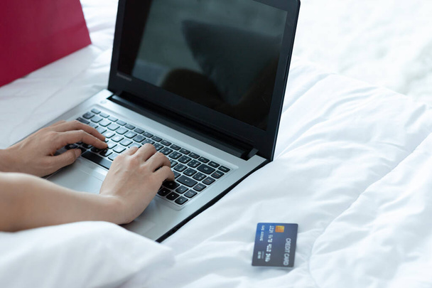 Asijka platí online. Nakupování on-line s kreditní kartou a notebookem na posteli v home.shopping on-line koncept. - Fotografie, Obrázek