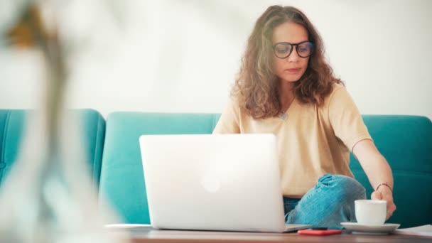 A young woman remote employee working from home with a laptop - Imágenes, Vídeo