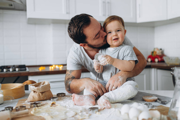 happy family in the kitchen. father and son preparing the dough, bake cookies - Фото, изображение