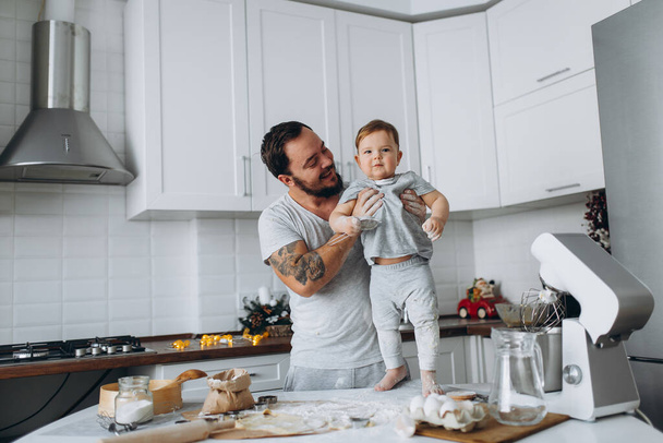 Onnellinen perhe keittiössä. isä ja poika valmistelee taikinaa, leipoa evästeet
 - Valokuva, kuva
