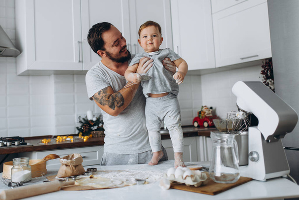 happy family in the kitchen. father and son preparing the dough, bake cookies - Foto, imagen