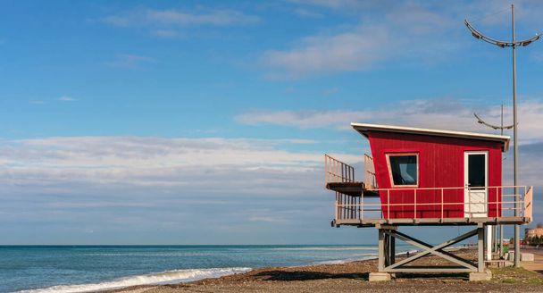Червона рятувальна вежа на пляжі з фоном блакитного неба
 - Фото, зображення