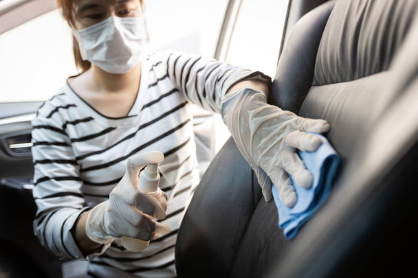 Woman wear protective glove,spraying alcohol antiseptic,disinfecting spray,cleaning on backrest,seat in car,protection during Coronavirus pandemic,Covid-19,wipe clean the surfaces with disinfectant - Zdjęcie, obraz