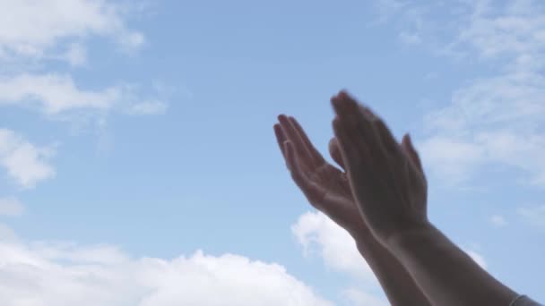 Tapsot! Női kéz tapsol a kék égbolt hátterében. Alacsony látószög - Felvétel, videó