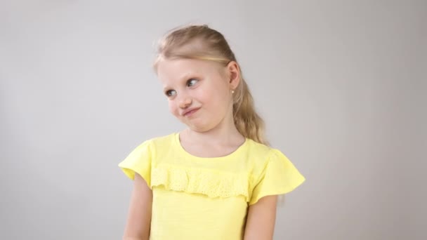 Las emociones de una niña. Retrato de una niña con un vestido amarillo sobre un fondo blanco
. - Imágenes, Vídeo