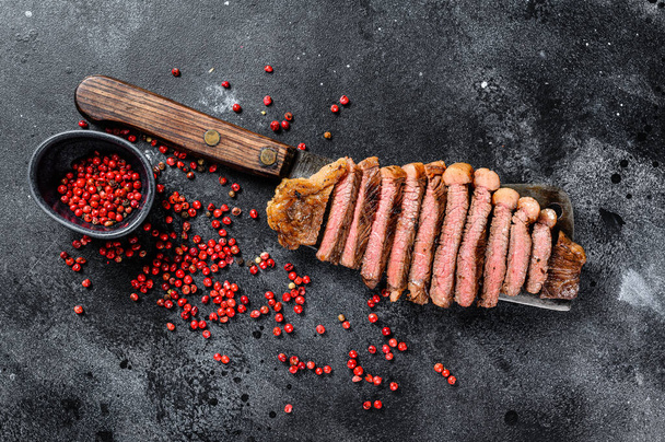 Grilled sirloin steak on a cleaver. The cooking medium. Black background. Top view. - Photo, Image