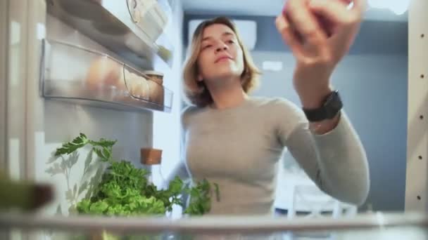 View Looking Out From Inside Of Refrigerator As Woman opens door takes an apple then puts it back and takes donut - Filmagem, Vídeo