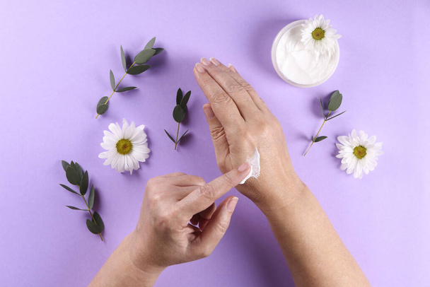 Revitalizing hand cream for healing and recovery after excessive use of soap and disinfectants. Adult woman applying moisturizing lotion. Copy space, close up, background, flat lay, top view. - Zdjęcie, obraz