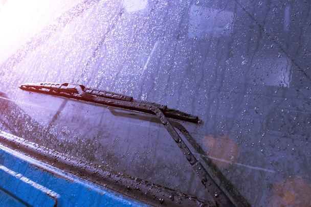 háttér textúra a kék szín az autó felülete és az autó ablaktörlők, ahol eső és hó csepp fut le a vihar után. a 2020-as év trendszíne, a közúti közlekedésbiztonság előmozdításának helye - Fotó, kép