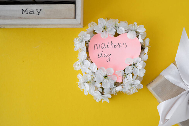 Bloky kalendáře z bílého dřeva a růžové květy ranunkulu s datem 10. května na Den matek. Selektivní zaměření s rozmazaným pozadím. - Fotografie, Obrázek