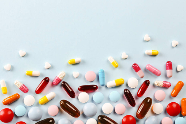 Flat lay composition with bunch of different colorful pills scattered over the table. Pile of opened medication on blue paper textured background. Close up, copy space for text. - Foto, Imagen