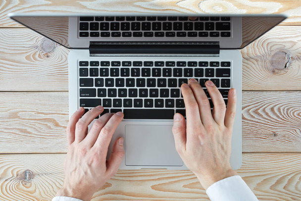 Vista superior de las manos del hombre escribiendo en el ordenador portátil en el día soleado. Coworking o trabajo en casa concepto de imagen
. - Foto, Imagen