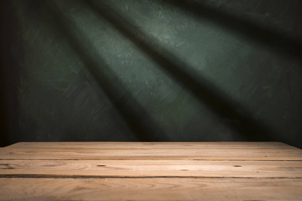 Mesa de madera vieja con la pared borrosa del bloque de hormigón en fondo oscuro de la habitación
. - Foto, imagen