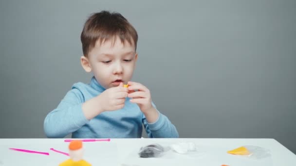 Beelden van vier jaar oude jongen beeldhouwen in plasticine op grijze achtergrond - Video