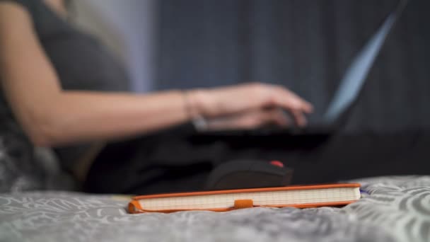 Νεαρή γυναίκα που εργάζεται με φορητό υπολογιστή χρησιμοποιώντας σημειωματάριο ως mousepad. Επιχειρηματίας κρατώντας σημειώσεις με στυλό - Πλάνα, βίντεο