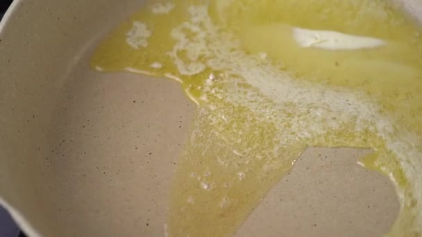 Moving frying pan with melting butter. Cube of butter melting sizzling browning in a pan in slow motion, preparation for cooking. - Filmagem, Vídeo