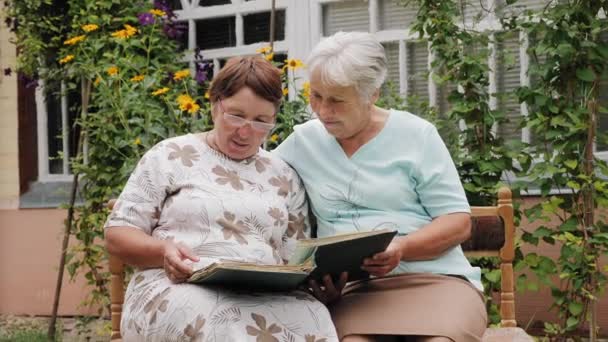 Ηλικιωμένες γυναίκες κοιτάζουν παλιές φωτογραφίες σε ένα άλμπουμ - Πλάνα, βίντεο