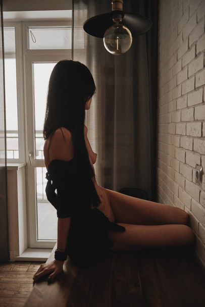 beautiful girl sitting on a table in a black shirt nude - Fotoğraf, Görsel