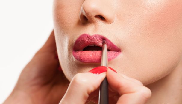Stylist applying lip gloss to a young woman - Фото, изображение