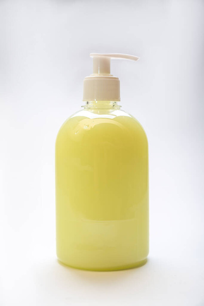 白い背景にディスペンサー付き黄色の防腐剤石鹸のプラスチックボトル。垂直方向 - 写真・画像