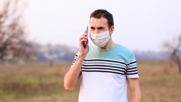 Scared adult man in panic call on phone and talk about bad news while wearing surgical mask outdoor. Epidemics, social media - Footage, Video