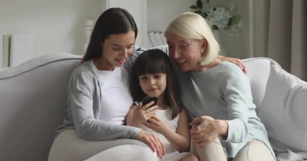 Happy three generations female family using smartphone apps at home. - Video, Çekim