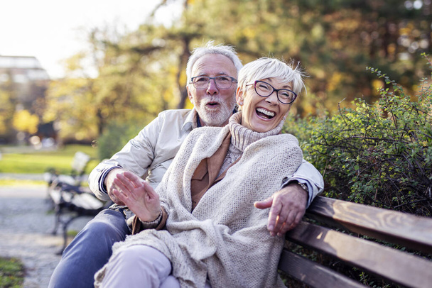 Old man and woman sitting on bench and smile - Fotoğraf, Görsel