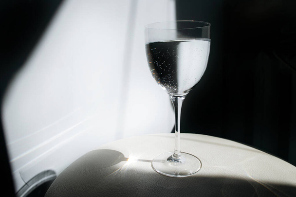 Ένα ποτήρι νερό σε λευκό φόντο. Ένα ποτήρι αντανακλά λάμψη. Διάφανο ποτήρι με κρασί. - Φωτογραφία, εικόνα