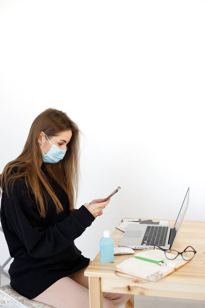woman working from home wearing protective mask. Cleaning her hands with sanitizer gel. Thermometer fever inspection. Working from home concept. Coronavirus, corvid 19 - Photo, Image