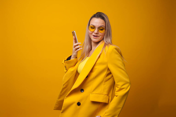 Stylish positive young woman on yellow background, copy space. - Foto, imagen