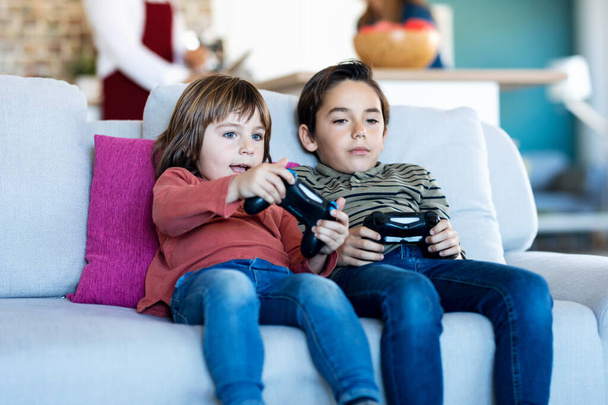 Постріл двох хороших братів, які грають у відеоігри, сидячи на дивані вдома
. - Фото, зображення