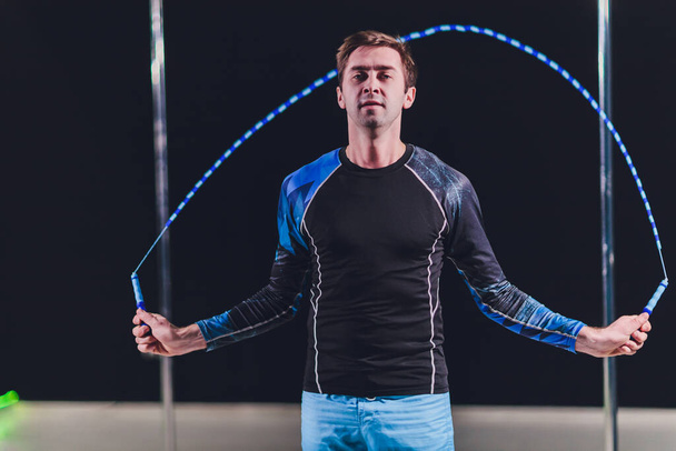 Muscular man skipping rope. Portrait of muscular young man exercising with jumping rope on black background. - Foto, Imagen